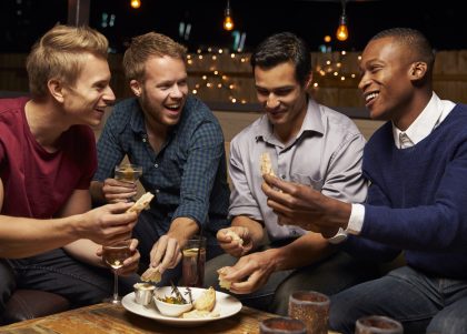 Group Of Male Friends Enjoying Night Out At Rooftop Bar
