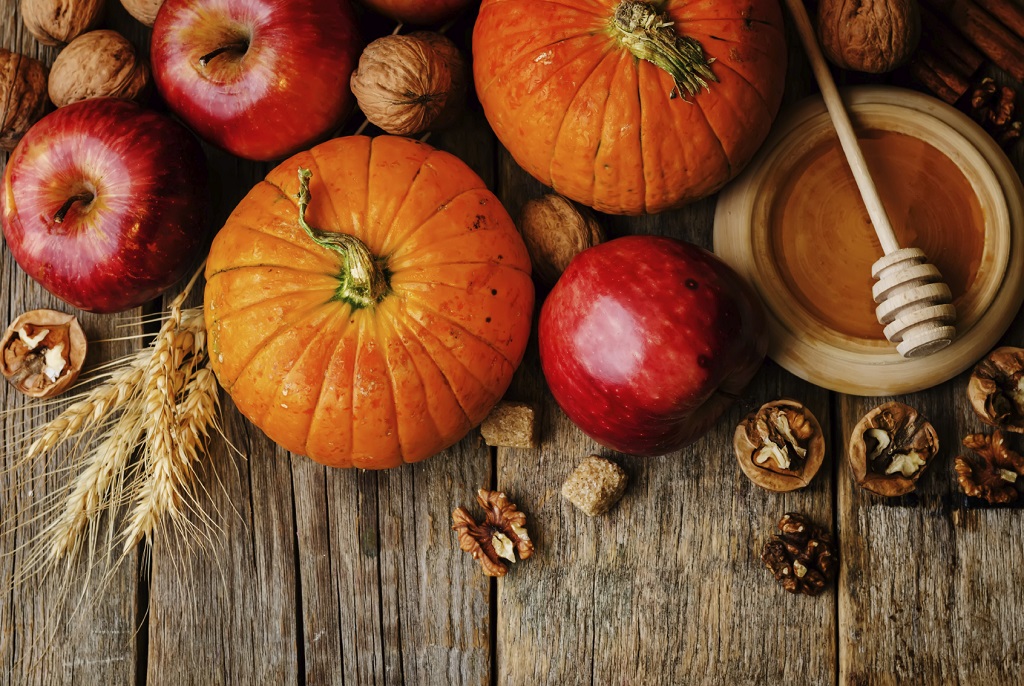 wood background with pumpkin, apples, wheat, honey and nuts
